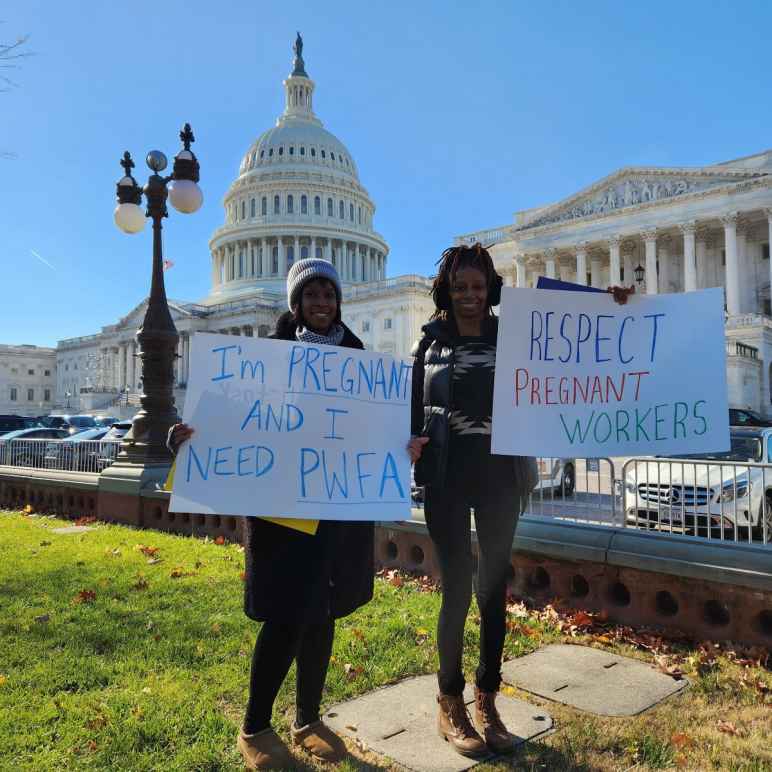 Two women holding signs outside of the US Capitol advocating for the Pregnant Workers Fairness Act